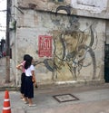 Two women watching. Traditional mural painting on the wall. Lhong 1919. Royalty Free Stock Photo